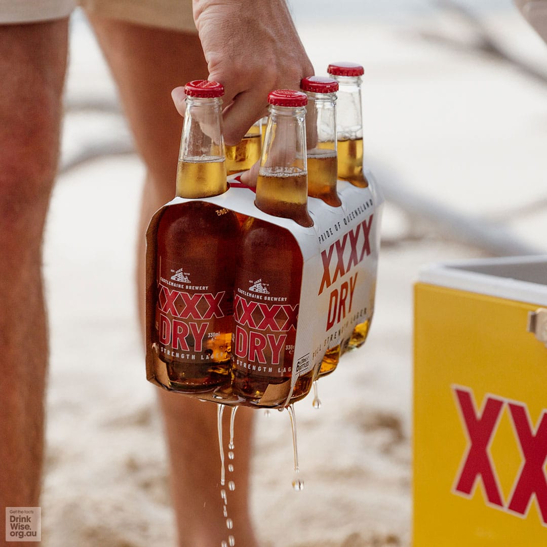 Carrying a six pack of XXXX Dry on the beach