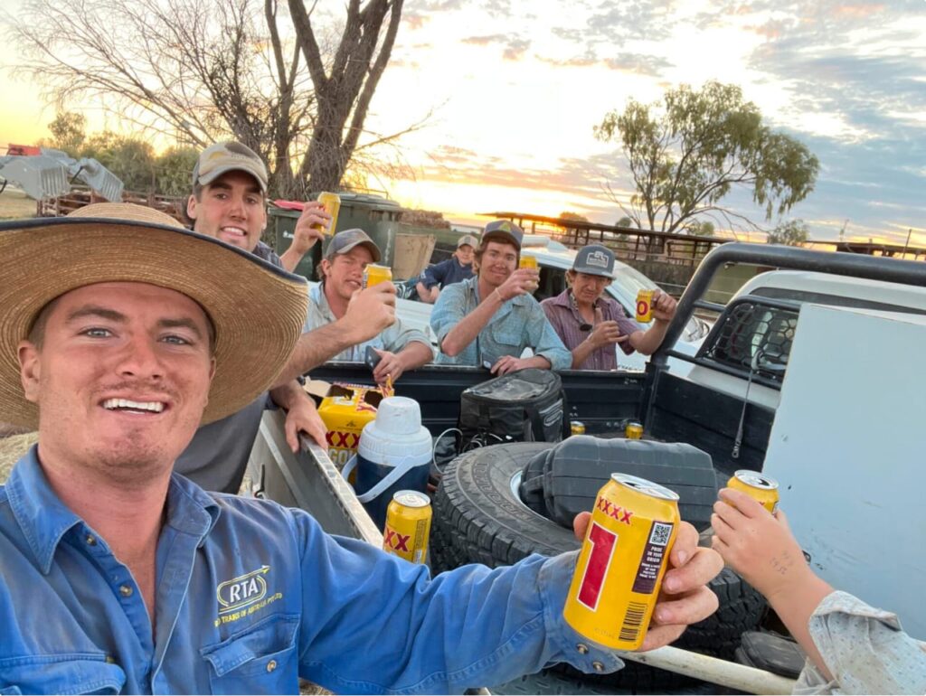 A group of mates enjoying XXXX gold over the back of the tray of their ute