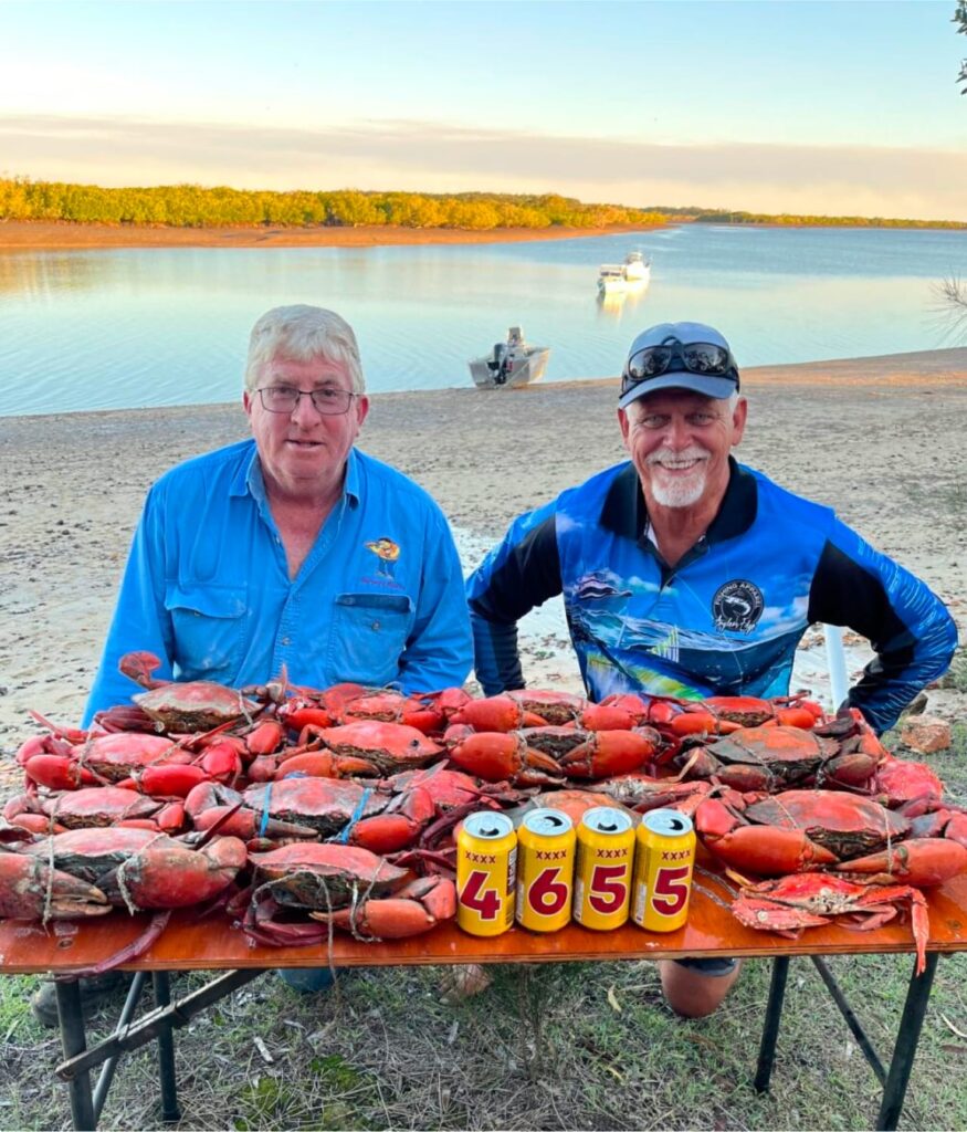 Two men with XXXX cans that say 4655 in front of a haul of crabs