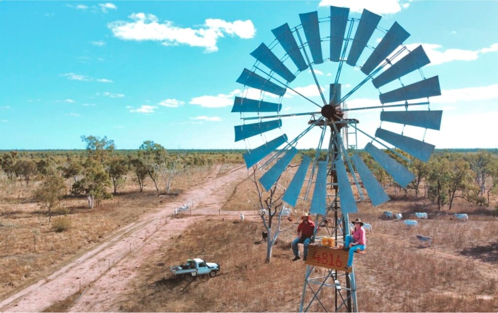 Two people from 4816 sitting on top of a windmill